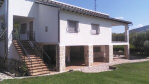 A two-story house with a stone foundation, a balcony on the upper floor, and a staircase leading to the entrance.