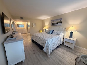 Une chambre à coucher avec un lit, des tables de chevet, une commode, un miroir et un tableau accroché au mur.