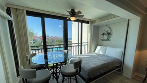 A hotel room with a balcony, a bed, a round glass table with chairs, and a ceiling fan. - Siesta Dunes 5-303, Come enjoy our little piece of Paradise! (Siesta Key)
