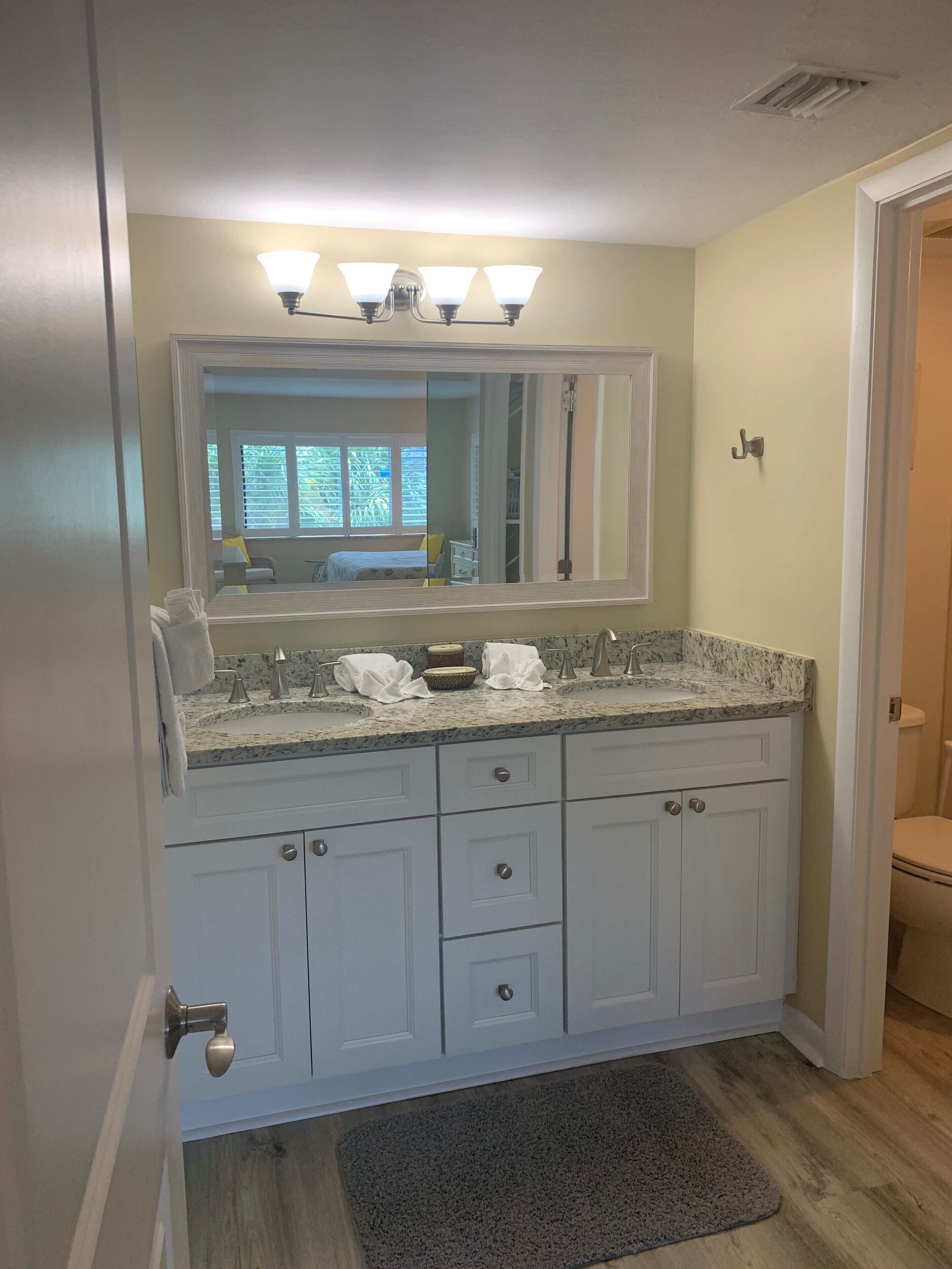 A bathroom with a double sink vanity, a large mirror, and a light fixture above the mirror.