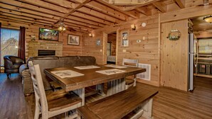 A wooden interior with a dining table, benches, a fireplace, and a ceiling fan. - 🌙 Midnight Wonder 🏔️ Twinkling Valley Lights, Hot Tub & Resort Pool (Sevierville)