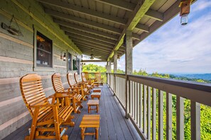 Una terraza de madera con mobiliario exterior y vistas del paisaje.