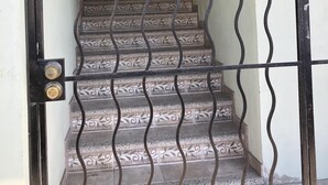 Un escalier orné de rampes en métal travaillées, menant à un espace intérieur.