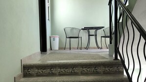 Un escalier orné de motifs décoratifs menant à un palier où se trouvent une table et des chaises.