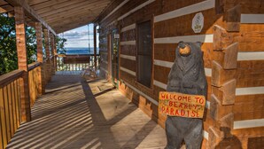 Uma cabana de madeira com varanda, placa de boas-vindas e vista para o oceano.