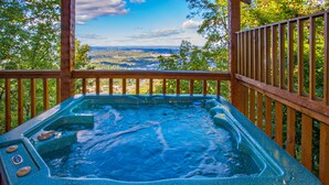 Banheira de hidromassagem com deck de madeira e vista panorâmica de um vale.
