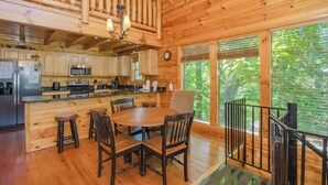 A wooden cabin with a kitchen, dining area, and a staircase leading to a loft. - Bearly Wet: Indoor Pool, Mtn Views! Hot tub, Wifi, Game Room, near attractions (Sevierville)