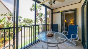 A balcony with a glass table, two chairs, and a ceiling fan. - Gulf/Pool View End Unit with extra balcony! (Sarasota)