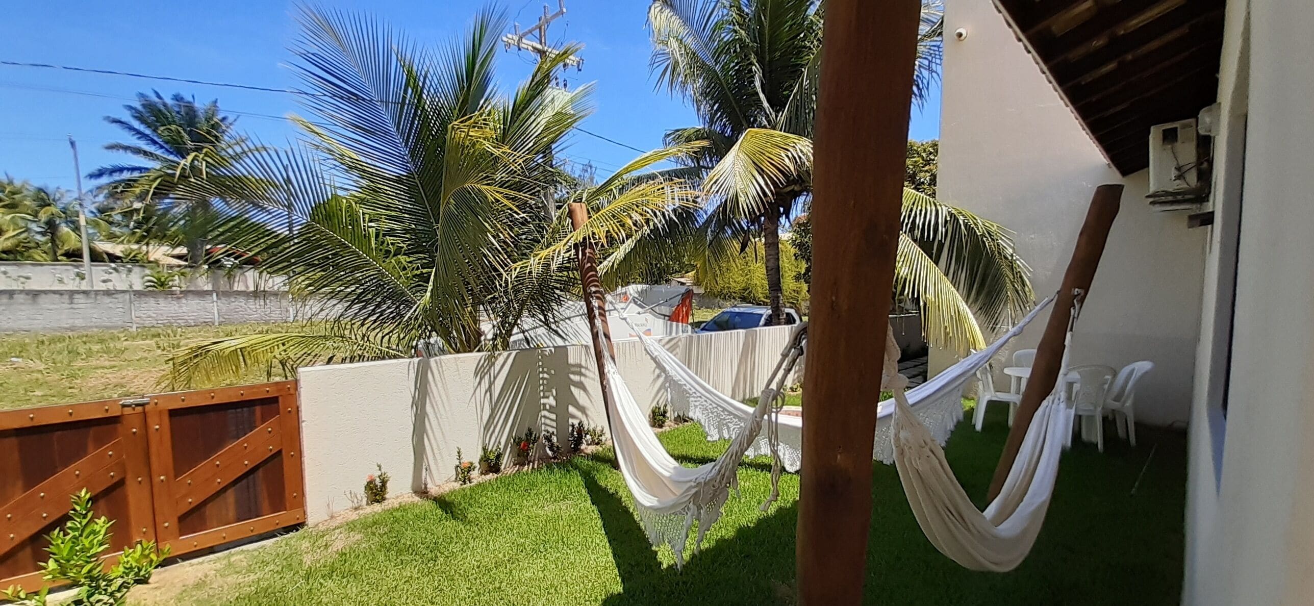 Quintal com rede, palmeiras e cerca branca.