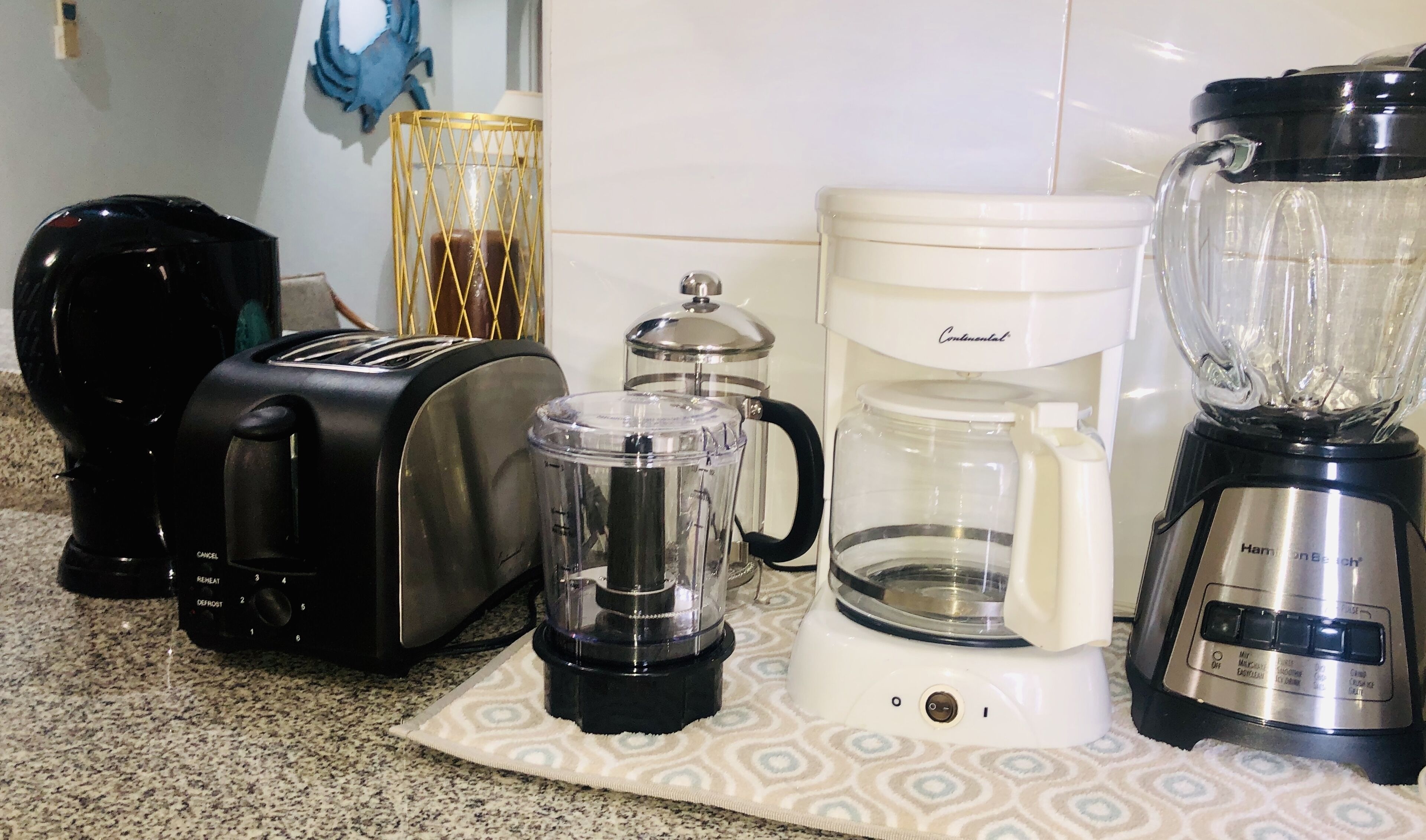 Uma cozinha com torradeira, liquidificador, cafeteira e um objeto decorativo na parede.