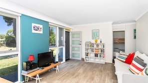 Un soggiorno moderno con una grande finestra, una libreria, un televisore e un divano.