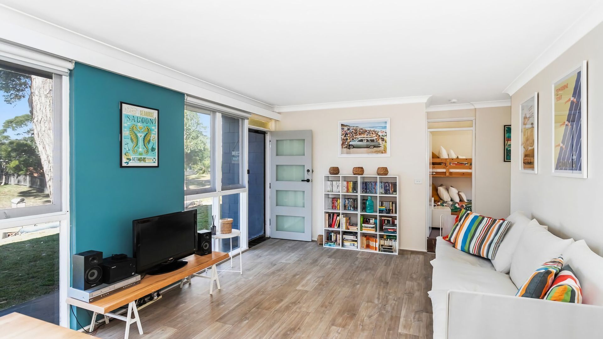 A modern living room with a TV, bookshelf, and a white sofa.