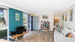 Ein modernes Wohnzimmer mit Fernseher, Bücherregal und einem weißen Sofa.
