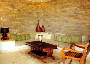 A living room with a stone wall, a sofa, a coffee table, a wooden chair, and decorative vases.
