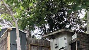 A small outdoor structure with a wooden deck, a water heater, and a hose connected to a faucet. -  Romantic Lakefront Escape: Massage, Yoga, Winery, Kayaks, SUPs, Krause Springs! (Spicewood)