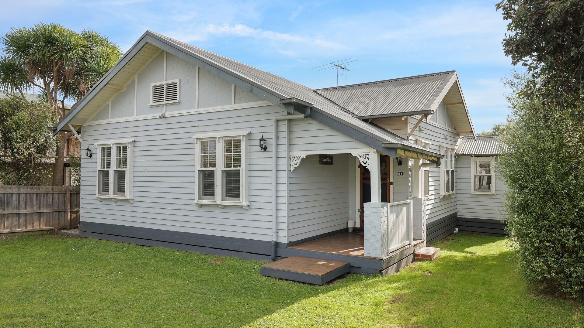 A two-story house with a front porch, a small deck, and a fenced backyard.