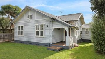 A two-story house with a front porch, a small deck, and a fenced backyard.