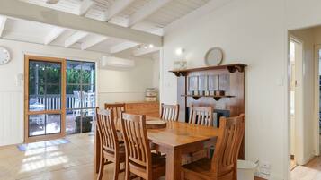 A dining area with a wooden table and chairs, a built-in shelf with a 'FAMILY' sign, and a view through a glass door to an outdoor patio.