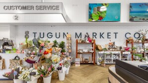 A flower shop with a white brick wall, a customer service desk, and a variety of flowers and plants for sale. - Seacrest 2 - Absolute Beachfront Tugun (Tugun)