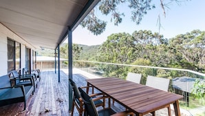 Una terraza de madera con una mesa y sillas, con vistas a un paisaje boscoso.