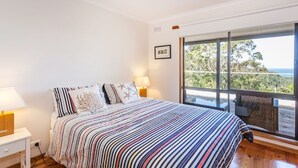 Un dormitorio con una cama grande, dos lámparas de noche y un ventanal con vistas al exterior.