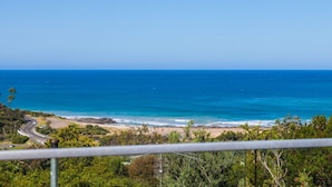Vista costera con una carretera que lleva a una playa, rodeada de vegetación.