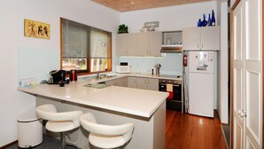 Une cuisine compacte dotée d’un îlot central, de tabourets de bar, d’un four à micro-ondes et d’un réfrigérateur.