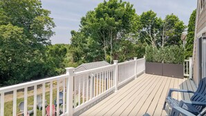 A wooden deck with white railings, surrounded by greenery and trees. - Walk to beaches & ferries ★ Snow's Creek Waterview (Barnstable)