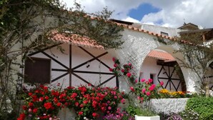 A building with a white facade, black window frames, and a tiled roof. There are colorful flowers in front of the building. - B&B Gli Archi Country Home (Giurdignano)