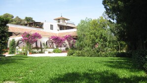 A villa with a spacious lawn, a patio area with outdoor furniture, and a garden with flowering plants. - B&B Gli Archi Country Home (Giurdignano)