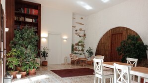 A cozy dining area with a wooden table and white chairs, surrounded by potted plants and a patterned floor. - B&B Gli Archi Country Home (Giurdignano)