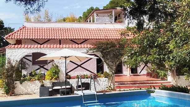 A poolside area with a white building, a red-tiled roof, and a pool. - B&B Gli Archi Country Home (Giurdignano)