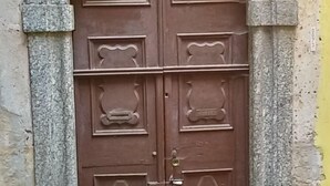Una puerta de madera grande y ornamentada con intrincados grabados, ubicada en un arco de piedra.