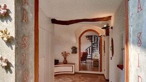 Un pasillo con una escalera de madera, un jarrón con flores secas y un diseño rústico en la pared.