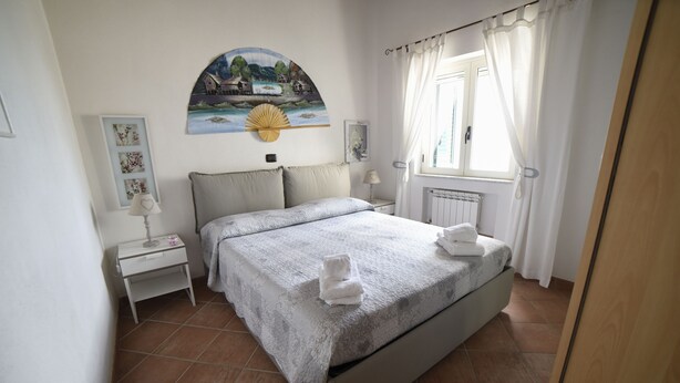 Ein ordentlich eingerichtetes Schlafzimmer mit einem Bett, einem Nachttisch, einer Lampe und einem Gemälde an der Wand.