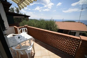 Un balcon avec une table et des chaises, une vue sur la mer et une clôture en treillis.