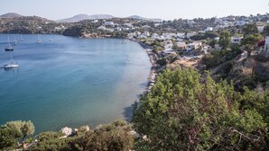 A coastal town with clear blue waters, boats, and a hillside with buildings. - Sunrise Bay. Modern Cycladic House near the beach with a magnificent view. (Leros)