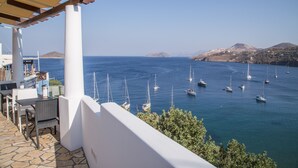 A terrace with outdoor seating overlooking a marina with sailboats. - Sunrise Bay. Modern Cycladic House near the beach with a magnificent view. (Leros)