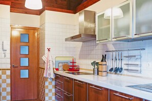 A kitchen with wooden cabinets, a stainless steel range hood, and a tiled backsplash. - Villa Los Alisios en Tacoronte (Tacoronte)