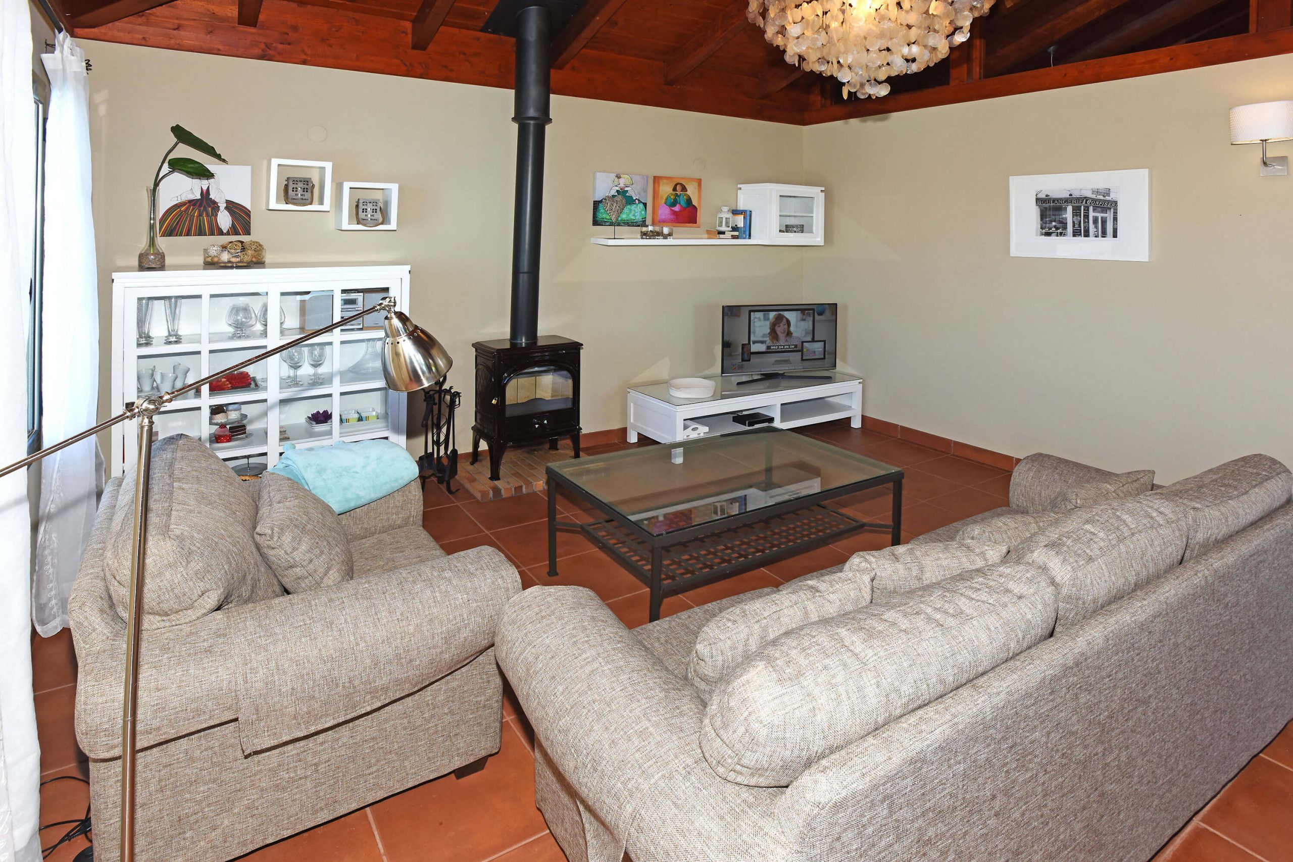 Una sala de estar con un sofá, una mesa de centro de vidrio, un televisor, una chimenea y un mueble con puertas de vidrio.