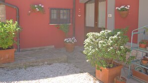Un bâtiment à la façade rouge, avec une porte et plusieurs plantes en pot.