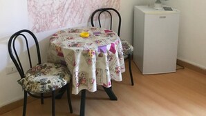 A dining area with a table set for two, a chair, a small refrigerator, and a painting of the Colosseum. - Holiday house in Palinuro center (Palinuro)