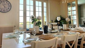 A dining area with a table set for a meal, a clock on the wall, and large windows. - Rocaille, villa with private pool, views, privacy, comfort and service (Pujols)