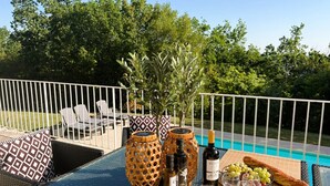 A glass table with a bottle of wine, a bowl of olives, a baguette, and a bottle of olive oil. - Rocaille, villa with private pool, views, privacy, comfort and service (Pujols)