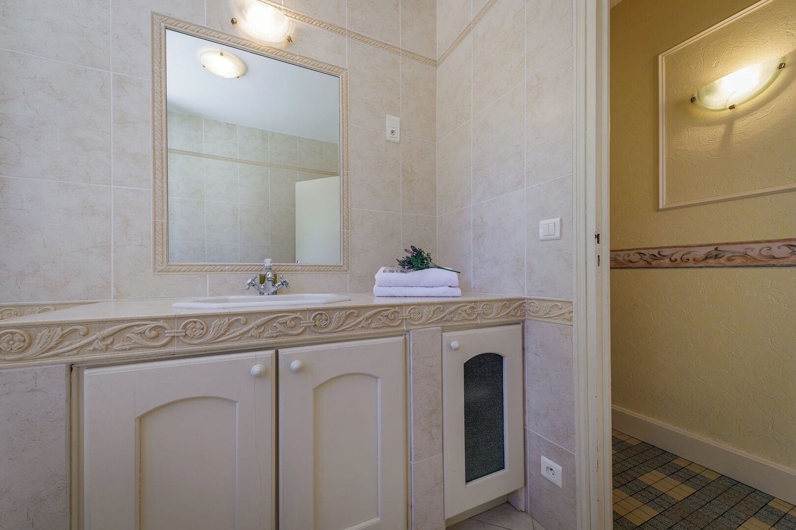 A bathroom with a sink, mirror, decorative molding, and a towel rack.