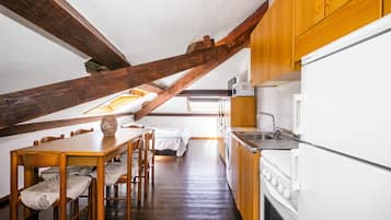 Eine kleine Küche mit Holzausbau, einem weißen Kühlschrank und einem Essbereich mit Tisch und Stühlen.