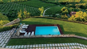 Vista aérea de una propiedad con piscina, sillas de descanso y césped bien cuidado.