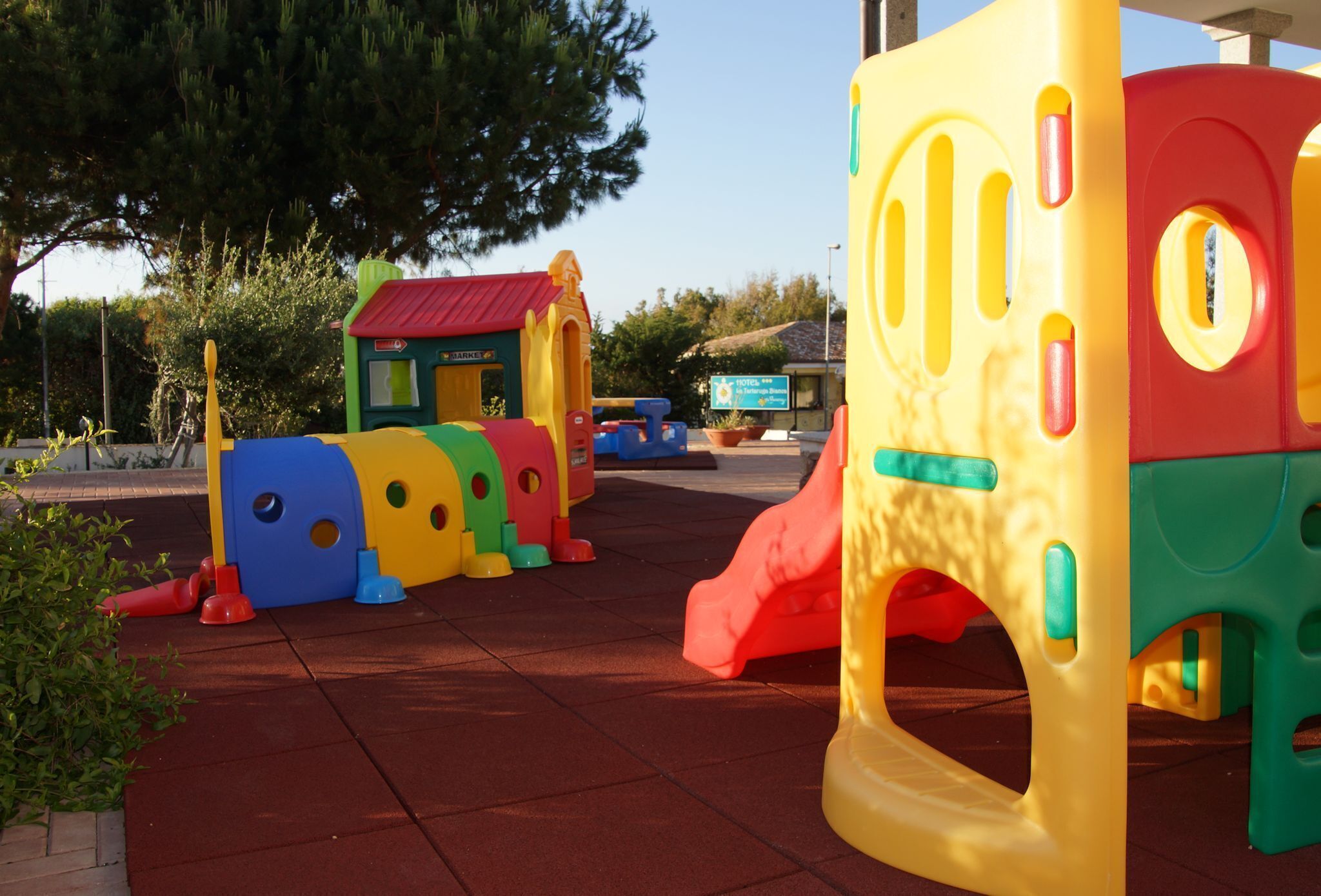 Ein Kinderspielbereich mit bunten Spielgeräten, darunter eine Rutsche und Kletterelemente.