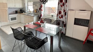 Eine moderne Küche mit weißen Schränken, einem Esstisch mit vier Stühlen und einem Kühlschrank.