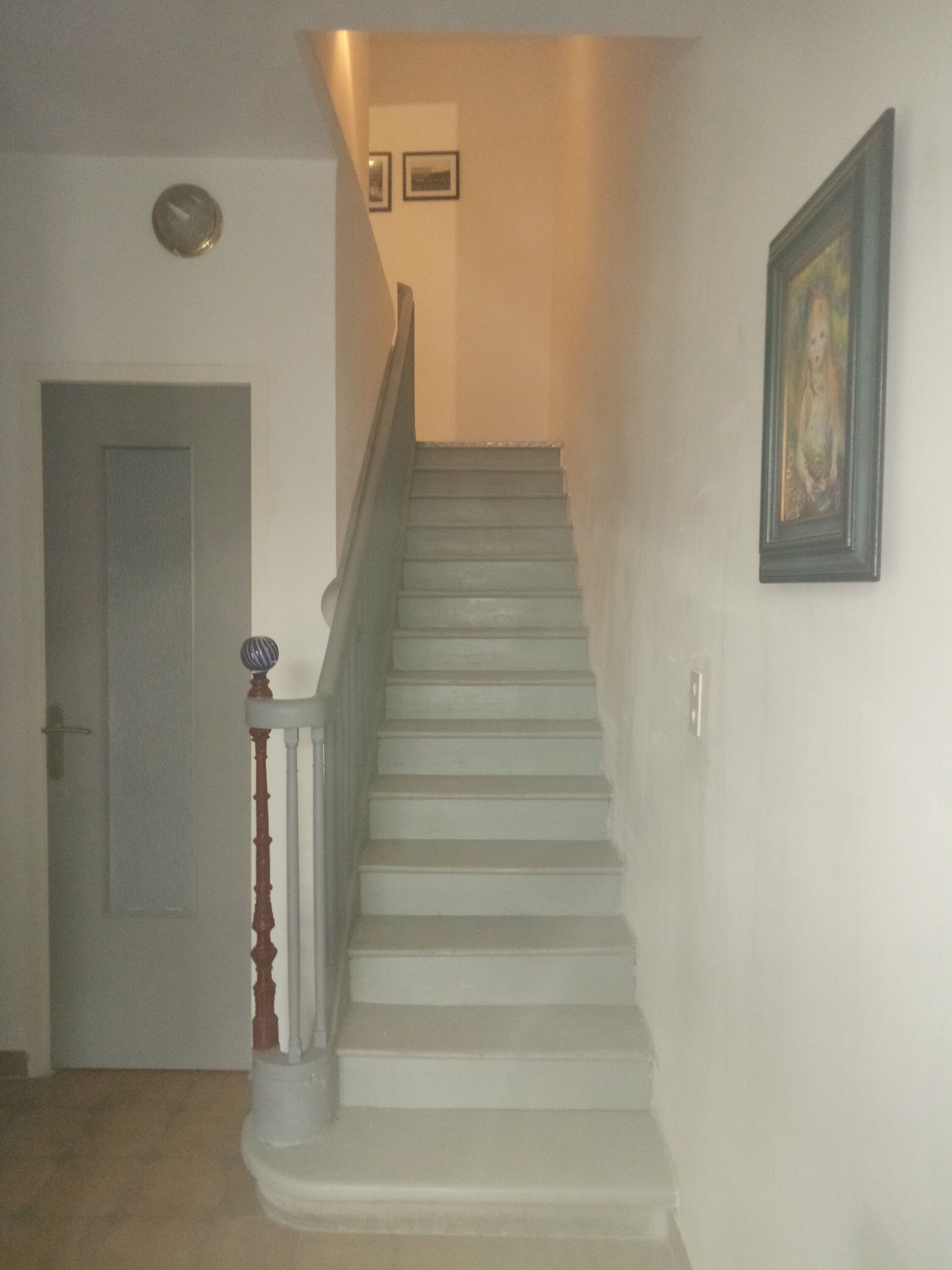 A staircase with a wooden handrail and a door at the bottom.